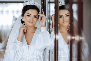 In the morning, an incredibly beautiful and luxurious bride, dressed in a white robe, poses by the...