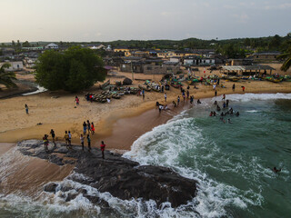 Aerial view of Ankwanda beach village community with sandy coast and swimmers, Central Region, Ghana.
