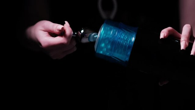 Sex toys for men. Male automatic telescopic masturbator in the hands of a girl on a black background. Male massager. Inserts a metal anal plug into the masturbator. Sex shop Adult store, toys for two
