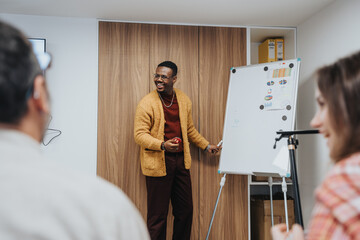 A cheerful African American man engages colleagues during a presentation in a modern office setting. - Powered by Adobe