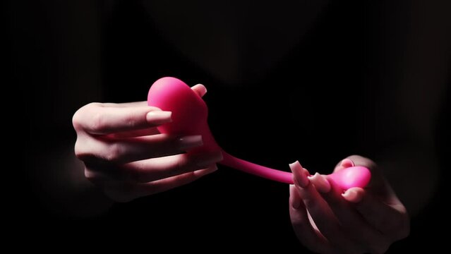 Pink vaginal vibrator for the G-spot in the hands of a girl on a black background. Sex Shop Products, Adult Gifts for Couples, Adult Store
