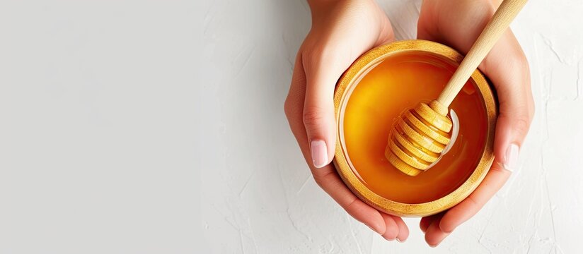 Female hands holding a bowl of bee honey and a wooden spoon Close up Elaboration of organic soap based on glycerin. with copy space image. Place for adding text or design