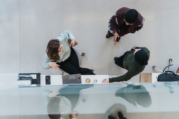 An aerial perspective captures two office workers engaged in a casual meeting at a standing desk.