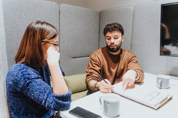 Two professionals engaged in a constructive business meeting within a contemporary office setting. They are focused on analyzing documents, suggesting teamwork and productivity.