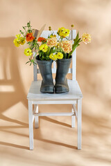 gardening, international women's day and floral design concept - flowers in rubber boots and straw...