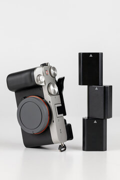 Camara fotogr&aacute;fica en posici&oacute;n artistica con tres bater&iacute;as, fondo blanco.