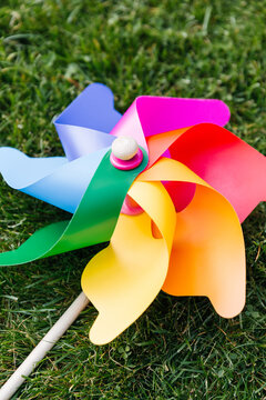 ecology, environment and sustainable energy concept - close up of multicolored pinwheel on green lawn or grass