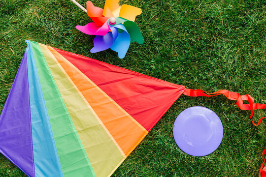 childhood and leisure games concept - close up of multicolored kite, flying disc and pinwheel on green lawn or grass