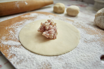 The filling for cheburek is laid out on a sheet of dough