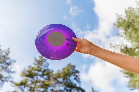 leisure games, toys and sport concept - close up of hand holding flying disc over sky