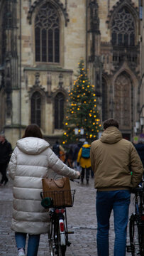 Man and woman walking with bicycles through the city at Christmas time. High quality photo