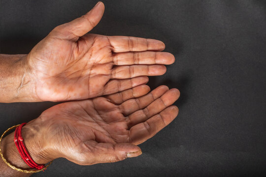 Close up of a senior woman's open hands on a black background. Conceptual photo.