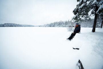 Traveler drinks hot drink by snowy lake