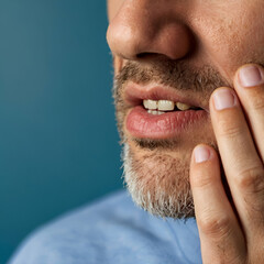 Capture the agony of a man with a toothache in this close-up portrait. Feel his distress as he presses his cheek, conveying pain and discomfort. Perfect for banner templates