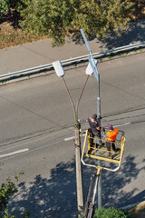 Workers installing a new street lamp and dismantling the old.