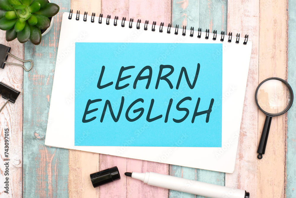 Poster text learn english on blue paper composition with stationery on color background. top view