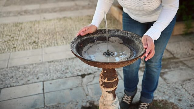 Woman drinks clean fresh water from a street water fountain while feeling the thirst. Urban spring with fresh water