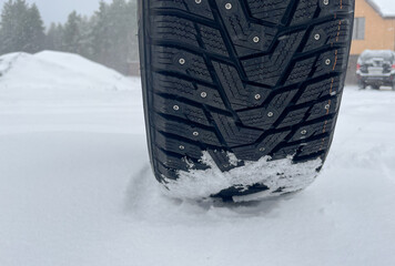 Winter tire with studs on snow, closeup