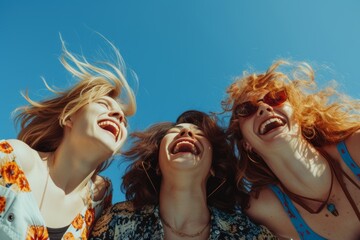 Jubilant Trio of Friends Embracing and Laughing Against a Clear Blue Sky