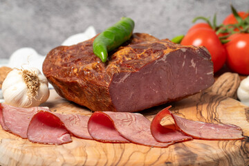 Smoked cold beef sirloin and slices on cutting board. Cold roastbeef slices on gray background. Close up