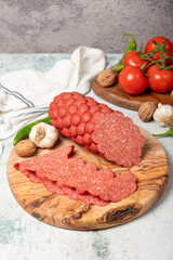 Sausage and slices on cutting board. Cold sausage slices on gray background