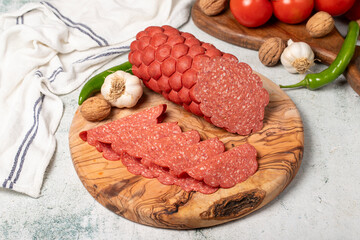 Sausage and slices on cutting board. Cold sausage slices on gray background