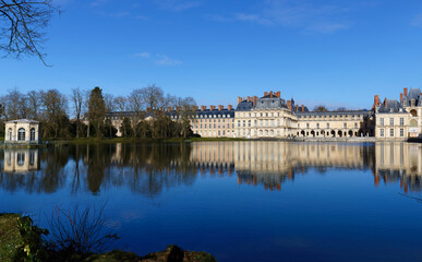Beautiful Medieval landmark - royal hunting castle Fontainbleau with reflection in water of pond. - 743134223