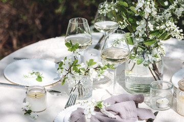 Rustic elegant eco friendly zero waste trendy wedding reception table decor with fresh spring apple cherry flowers in bloom. Beautiful marriage decoration, holiday event outdoors in the family garden