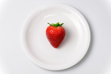 白いお皿に乗った赤く熟した苺