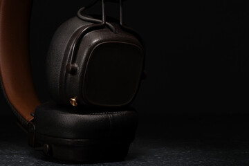 
audifonos inalambricos de color café oscuro con control incorporado en fondo oscuro y piso con...