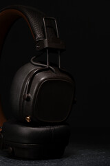 
audifonos inalambricos de color café oscuro con control incorporado en fondo oscuro y piso con textura a piedra
