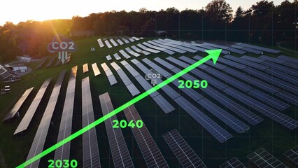 3D graphic of net-zero concept, with CO2 decreasing to zero by the year 2050 for climate action. Aerial of solar panel array during sunset