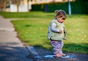 Rascal little female child with braids jumping in a muddy puddle on a sunny spring day. Scoundrel 2...