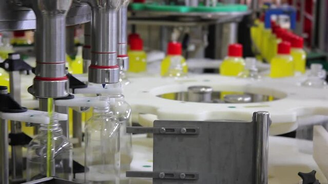 Close up of liquid detergent on automated production line. Machinery for bottling, filling plastic bottles with detergent. Moving on production line bottling and packing