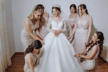 Bridesmaids rejoice in the morning, helping to fasten the buttons on the wedding dress and prepare...