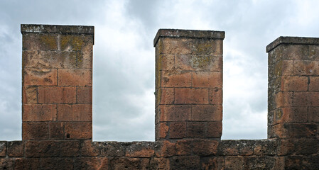 Detail of the ancient brick wall surrounding the city of Orvieto in Italy, with clouded sky