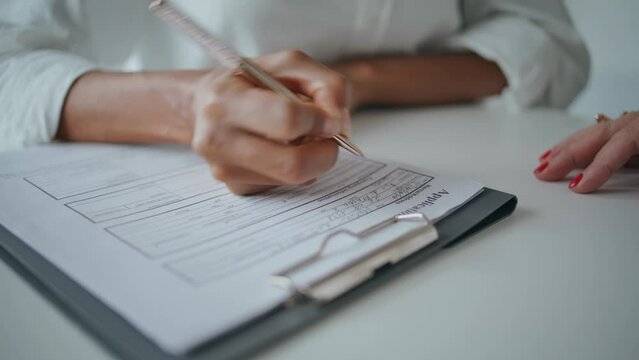 Closeup hands writing application papers on desk. Patient signing insurance form