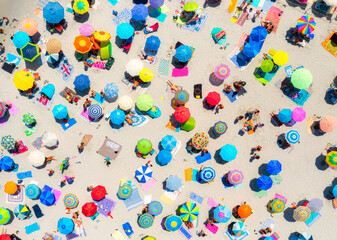 Aerial view of colorful umbrellas on sandy beach on summer sunny day in Sardinia, Italy. Tropical landscape. Travel and vacation background. Top down view from drone. Tropical pattern. Seaside