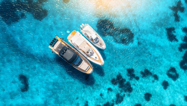 Aerial view of luxury yachts and boats on blue sea at sunset in summer. Travel in Sardinia, Italy. Drone view from above of speed boats, yachts, sea lagoon, transparent azure water. Seascape. Seaside