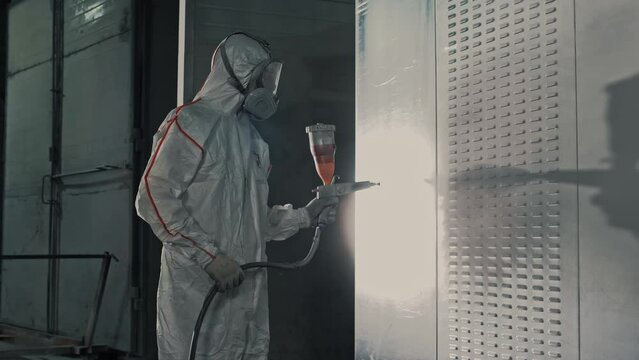 Painting a metal structure with powder paint using a sprayer under the influence of an electric field in the factory. Slow motion