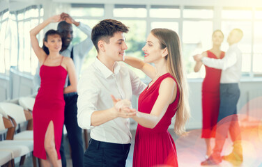 Couple of young guy and young woman dancing waltz in studio