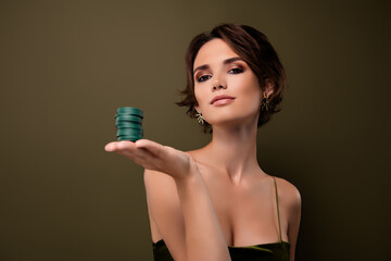 Photo of attractive wealthy girl demonstrate pile stack casino chips on hand isolated over green...