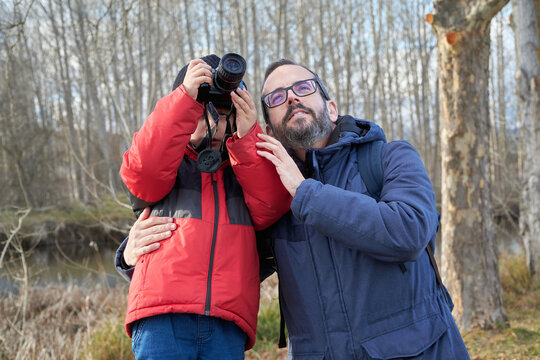 Father and little son taking pictures in forest with photo camera