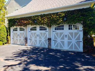 Closed garage doors covered with ivy. Three sections of private garage doors.