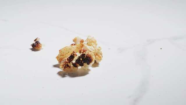 Dropping a piece of roasted cauliflower onto a counter top