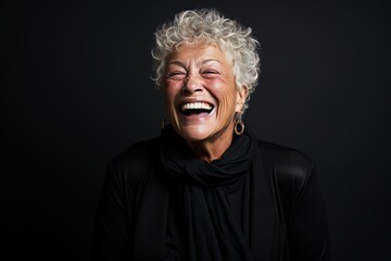 Portrait of a happy senior woman laughing on a black background.