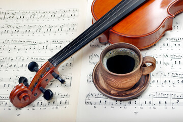 beautiful antique violin on a background of notes and cup of coffee 
