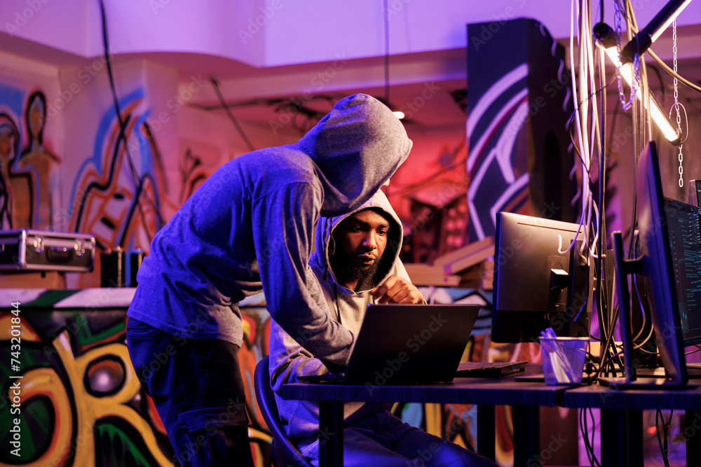 Poster criminals hacking on laptop together and planning ddos attack on website. two hackers in hoods check
