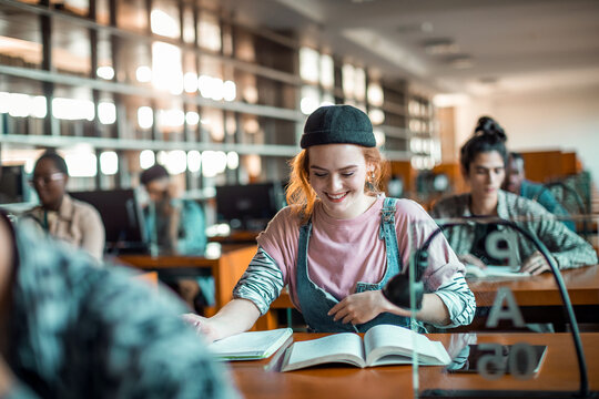 Smiling Female College Student Reading At Library