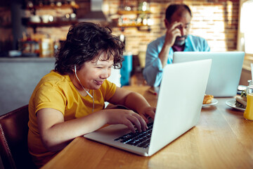 Father and son using laptop at kitchen table